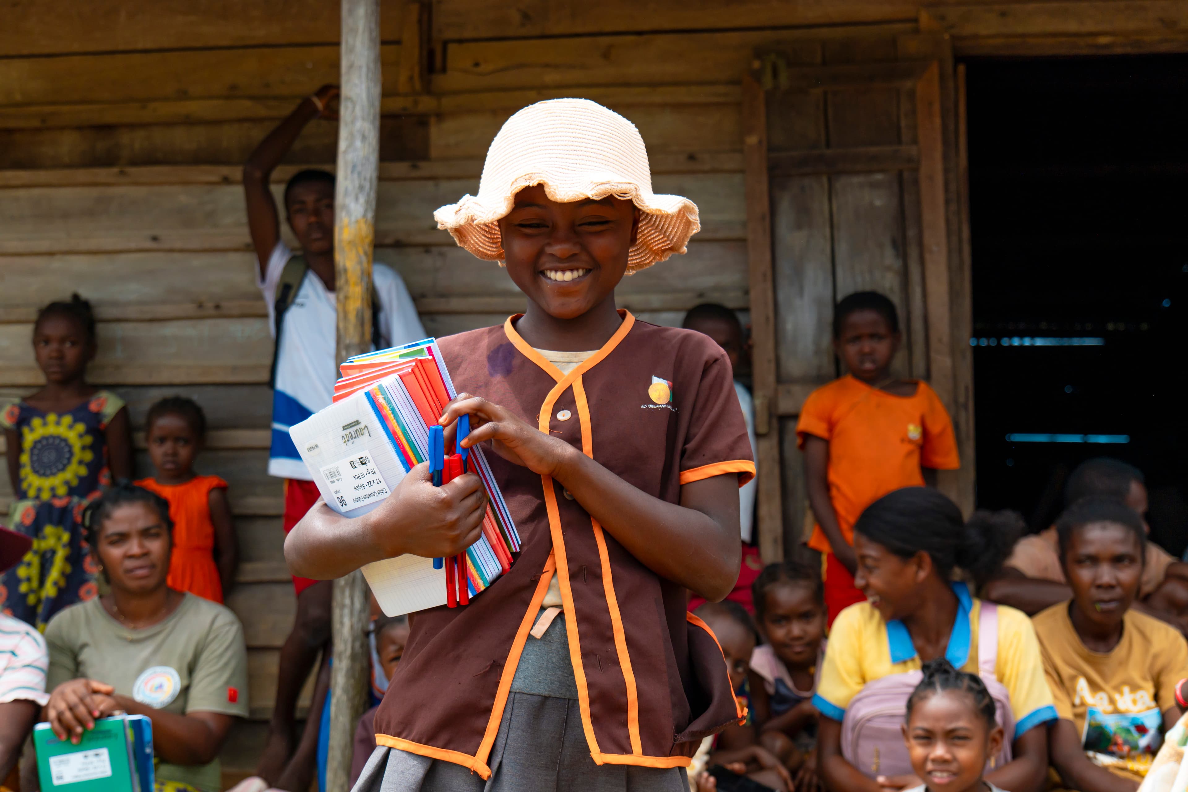 Enfant souriant avec cahiers scolaires remis par VA